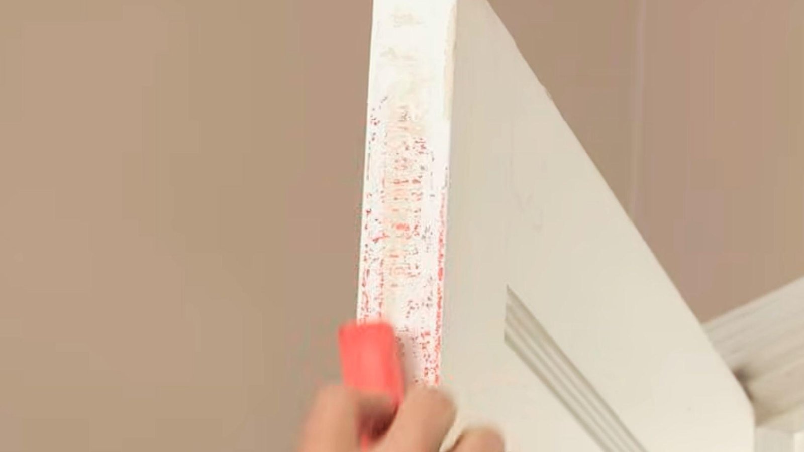 Applying chalk to the edge of a white interior door to identify where the door sticks against the frame.