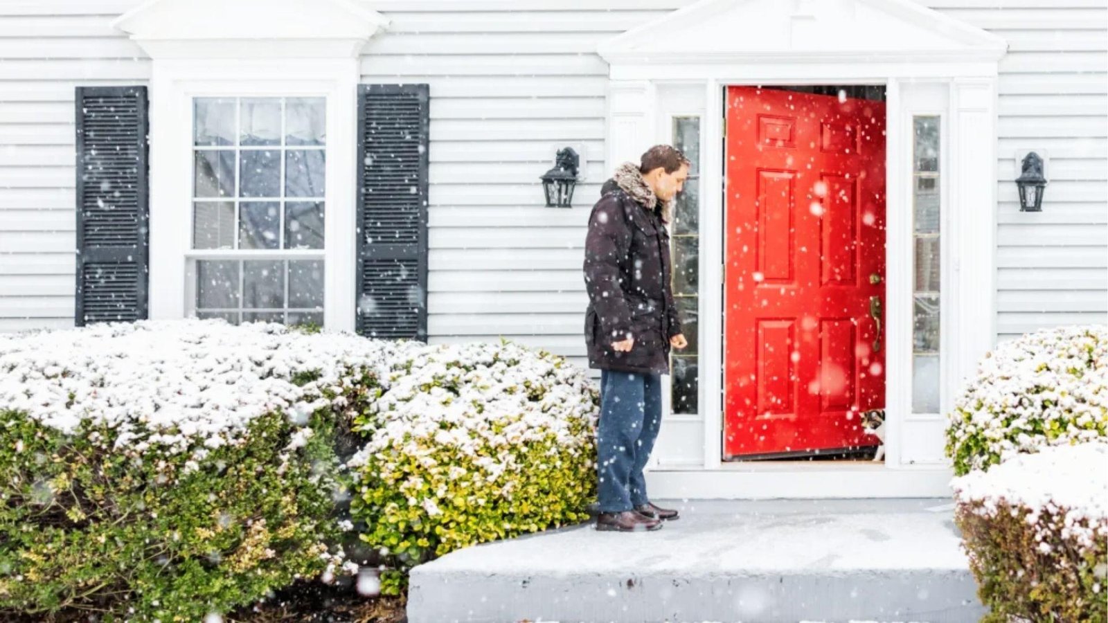 Red insulated exterior door in snowy weather keeping home warm and energy efficient during winter