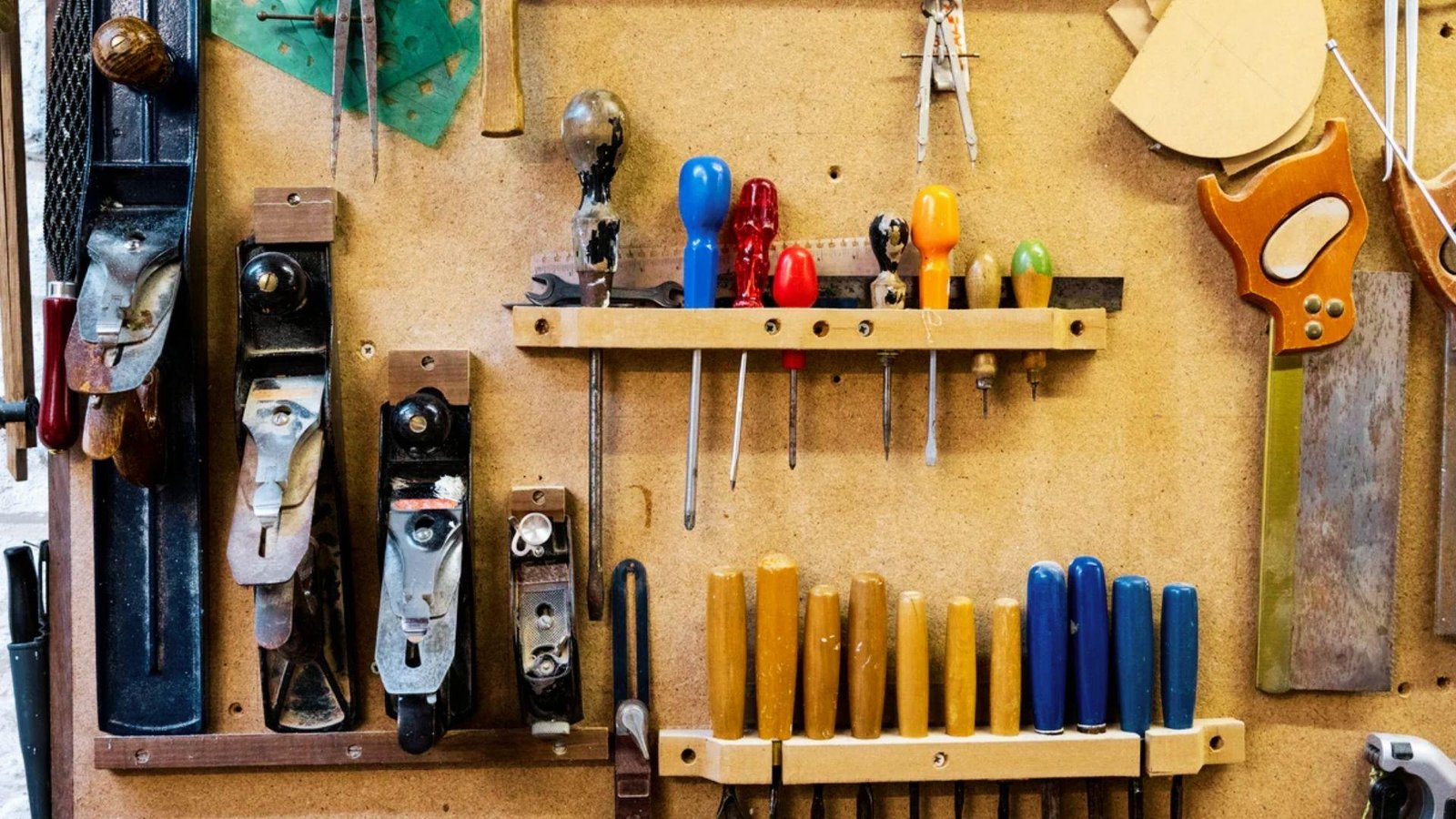 Organized woodworking tools including hand planes, screwdrivers, and saws mounted on pegboard for DIY door repair projects