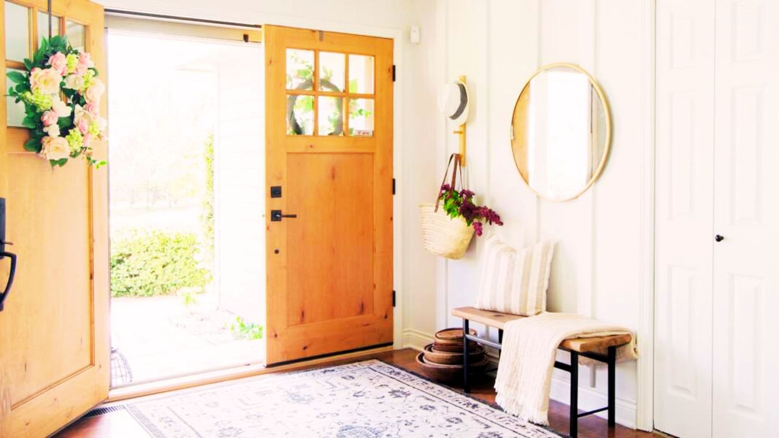Cozy farmhouse board and batten entryway with white walls, wooden bench, and neutral decor.