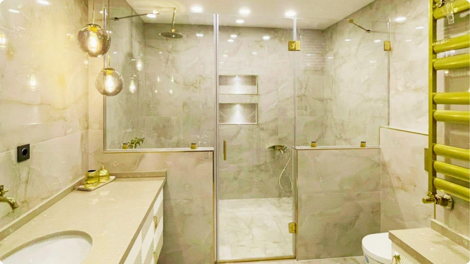 Classy marble bathroom showcasing a frameless hinged shower door with gold hardware.