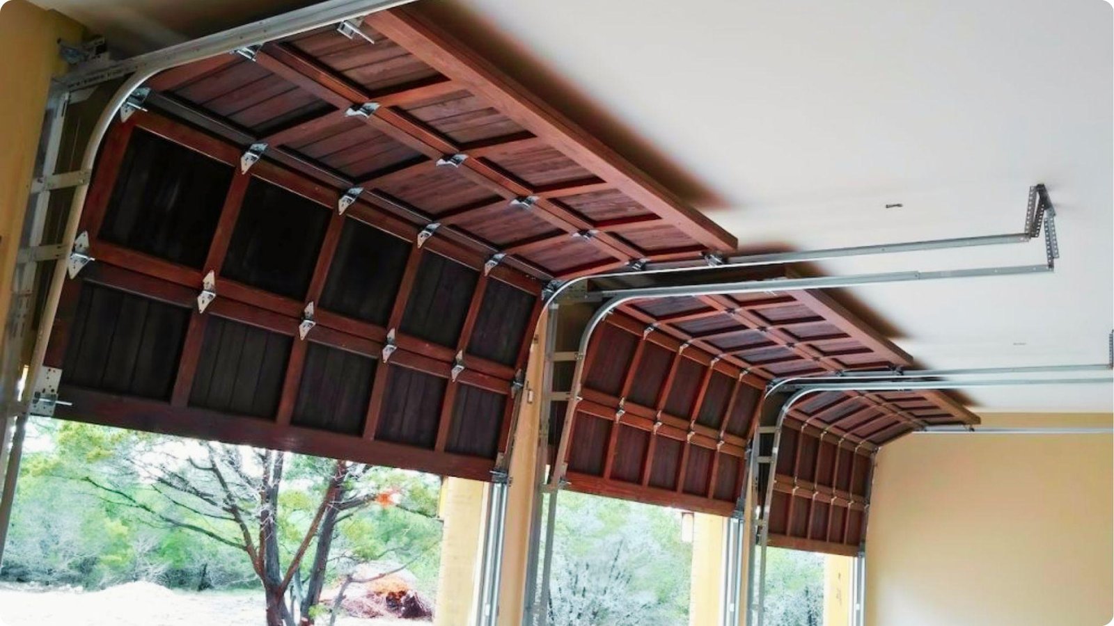 Three wooden garage doors shown from inside, partially open along ceiling tracks.