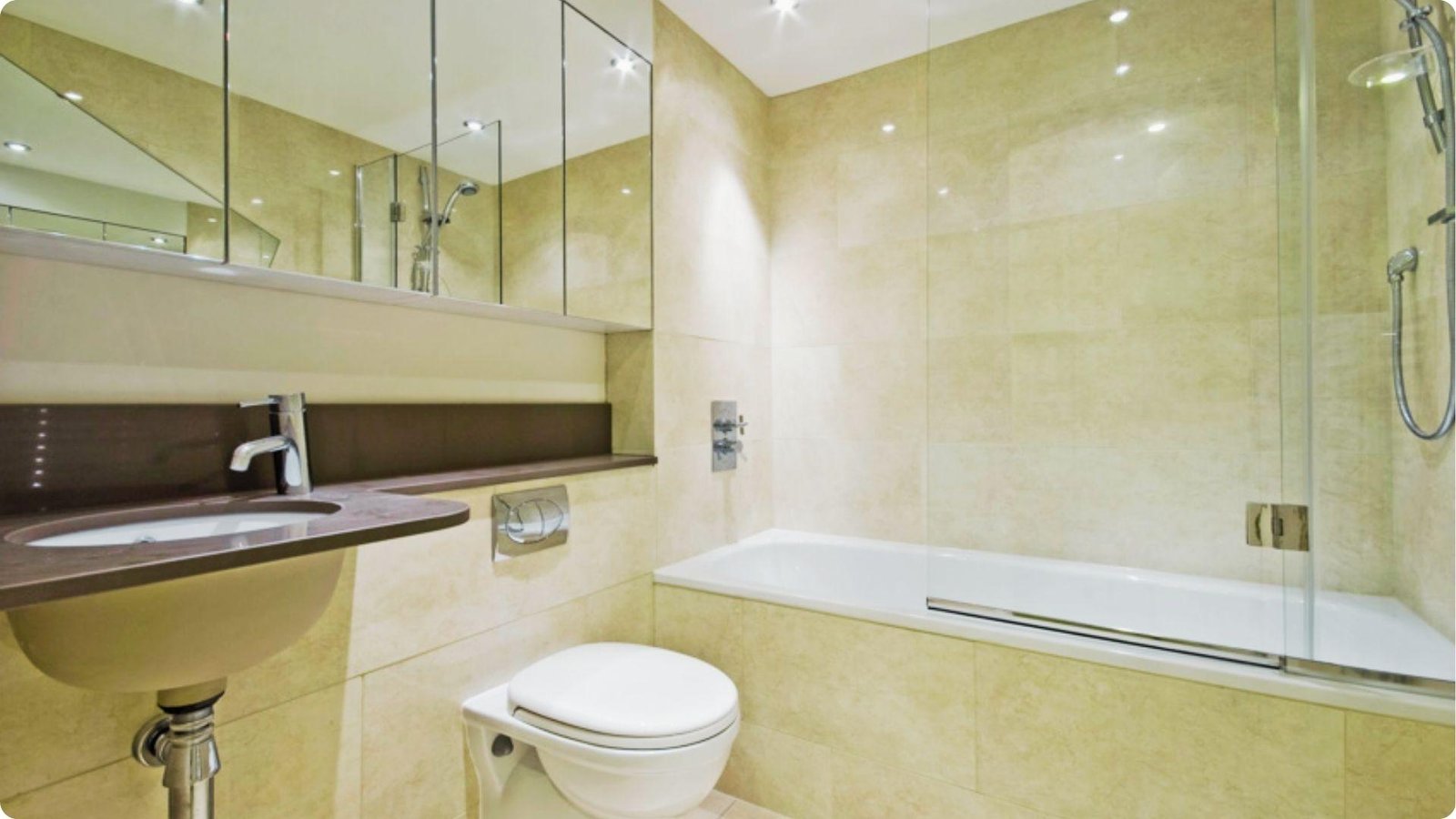 Compact bathroom with beige tiles featuring a frameless half glass shower door on the bathtub.