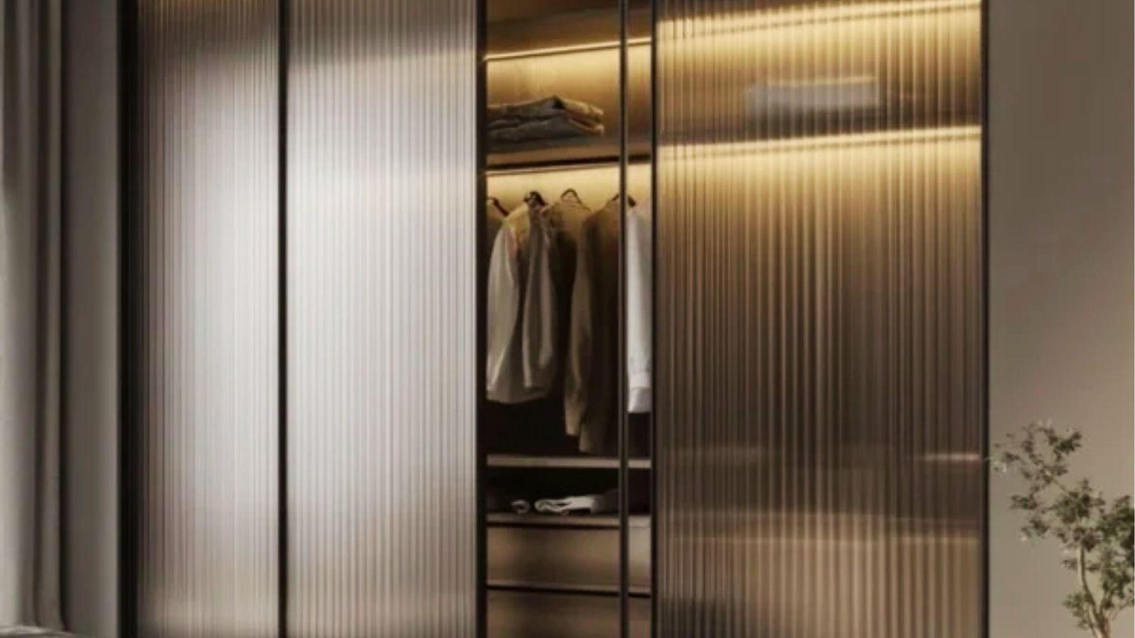 Modern bedroom wardrobe with reeded etched glass sliding doors offering privacy while allowing warm interior light to glow through.