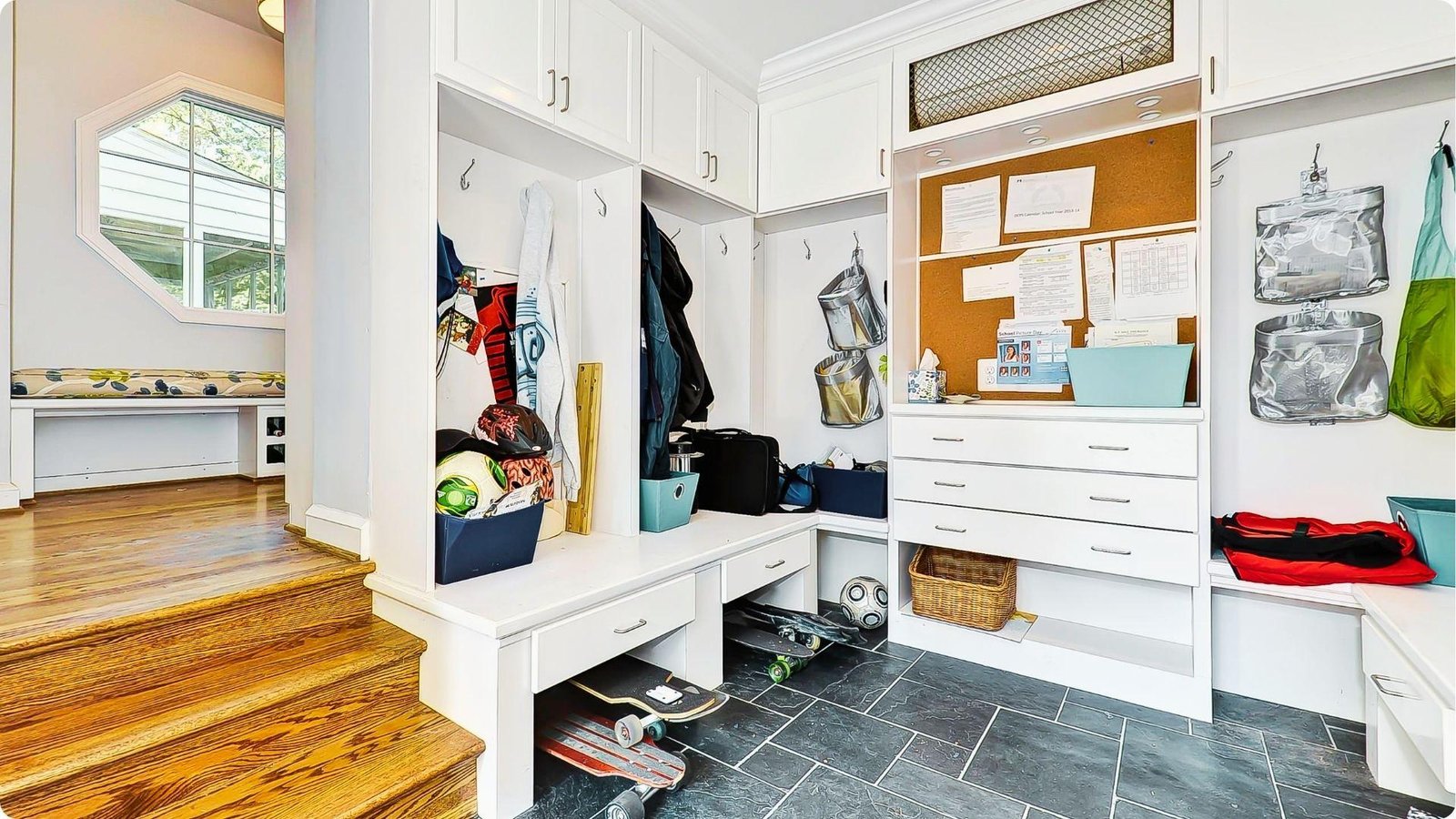 Bright white mudroom with built-in cubbies, bench seating, and overhead cabinets.