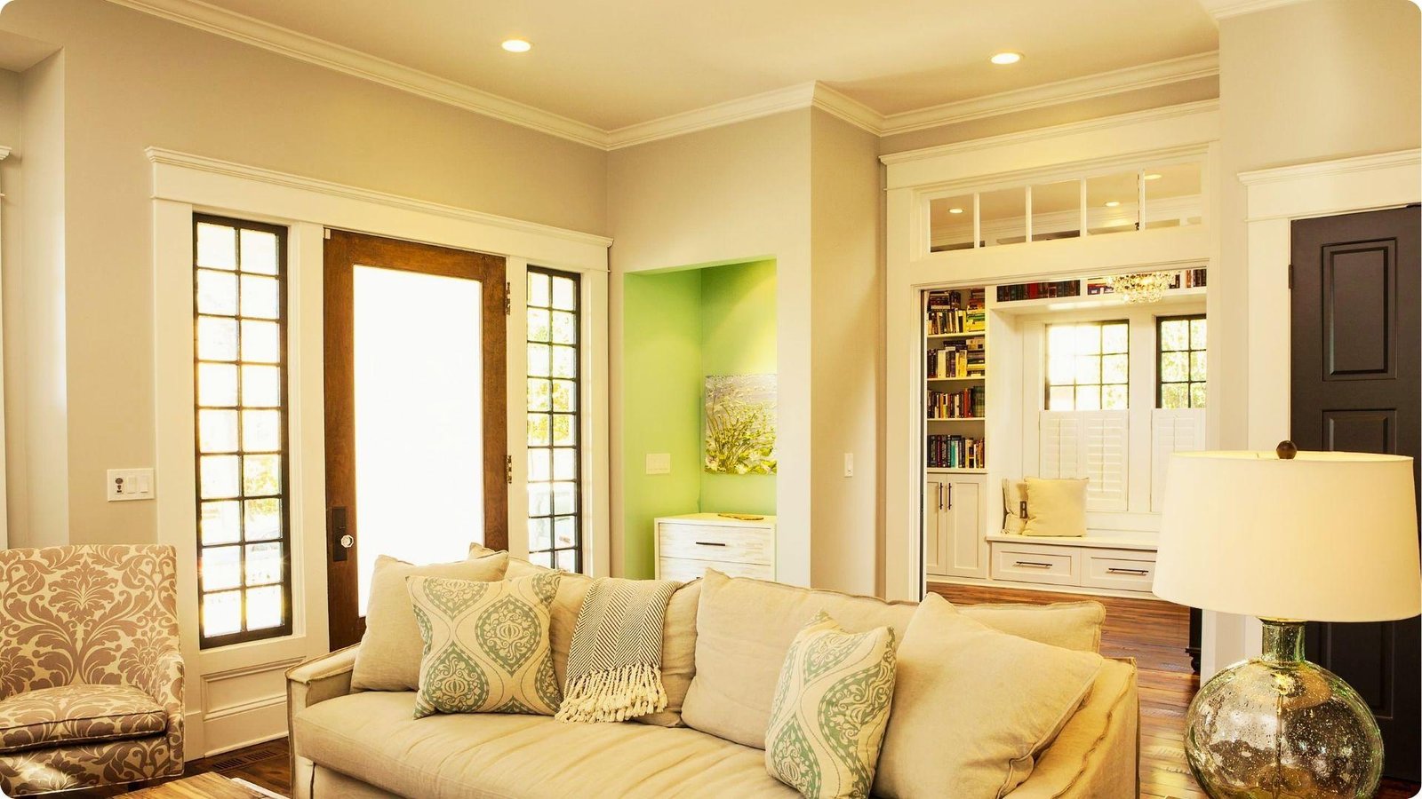A light-filled living room uses a sofa and armchair to buffer the front door, creating a defined seating area.