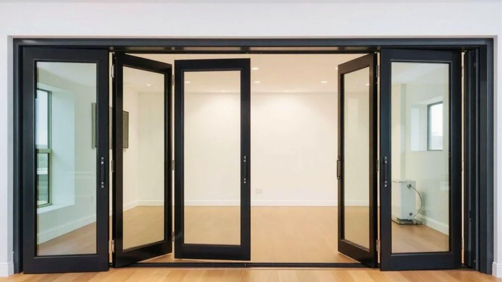 Modern black frame glass bifold doors partially open into bright room with wood flooring