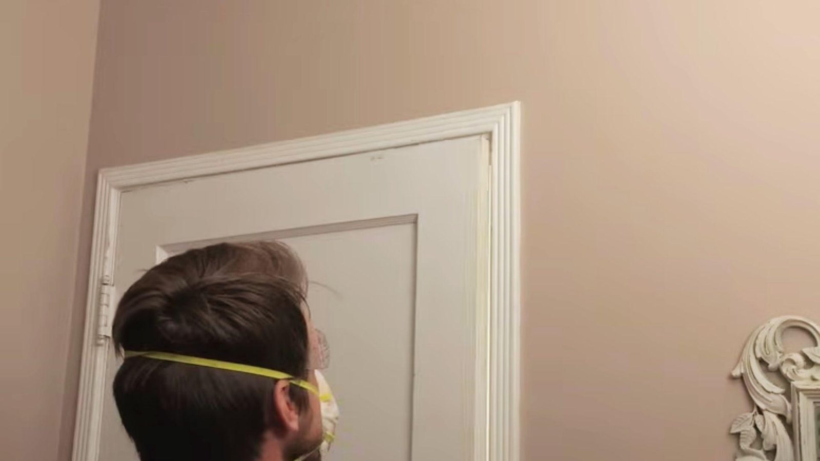 Homeowner checking the alignment of a repaired door after sanding and hinge adjustments.