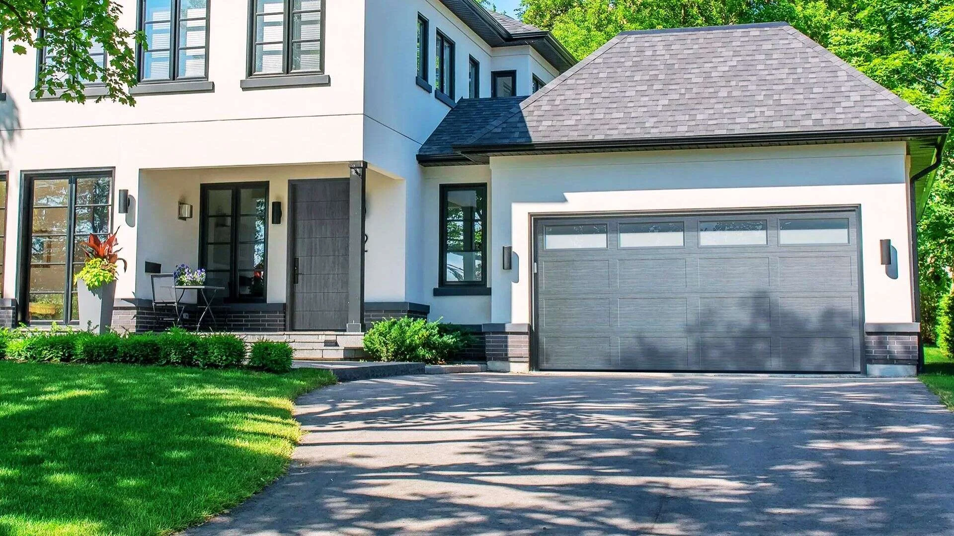 Grey suburban house with trendy black garage door and modern exterior styling.