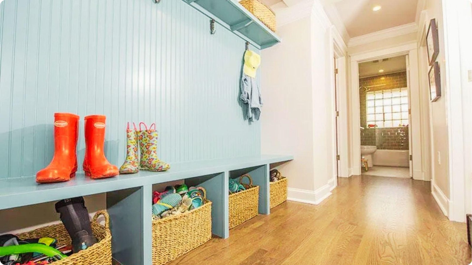 Light blue beadboard mudroom with a long bench and woven baskets under cubby storage.